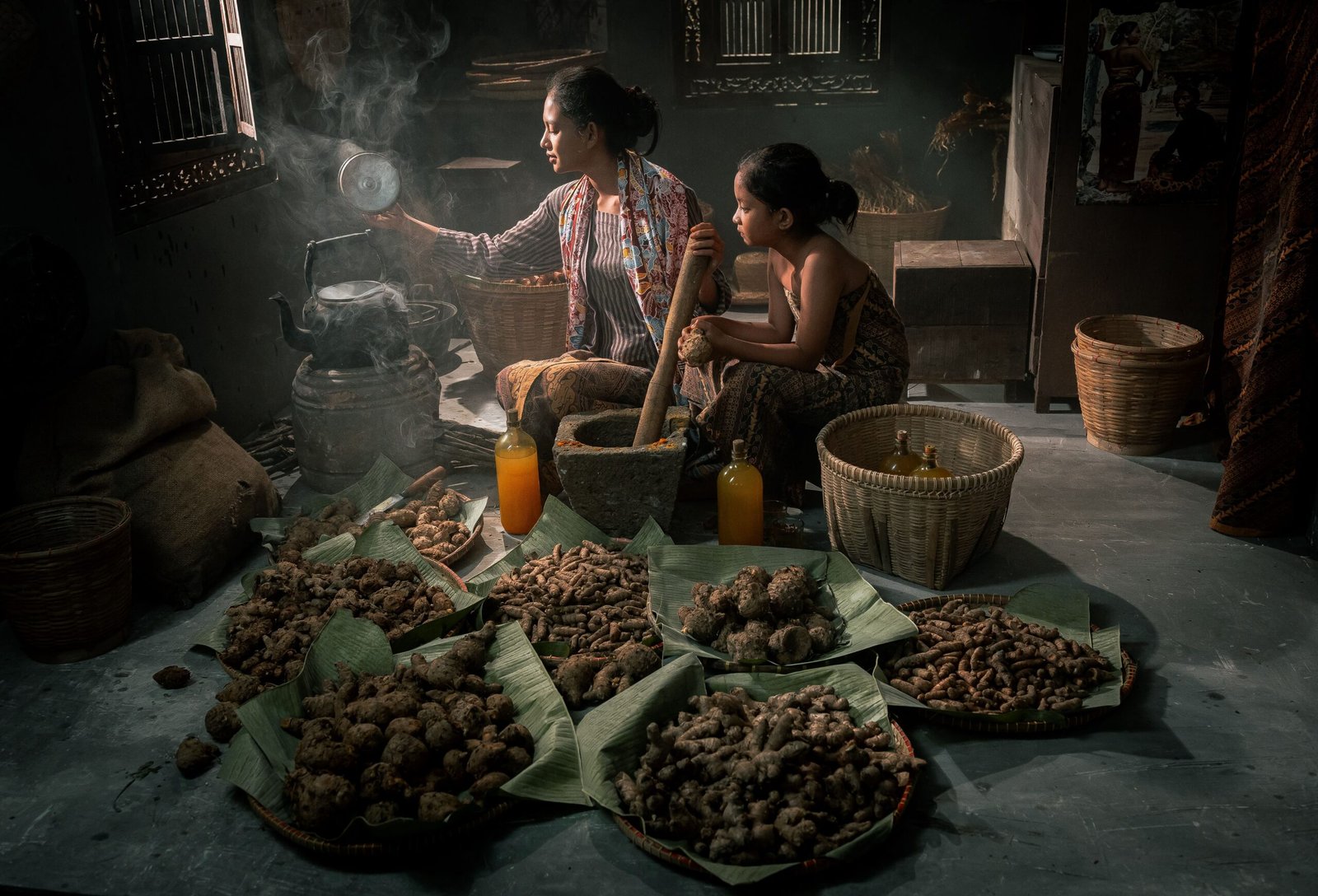 Indonesian woman and child in traditional kitchen preparing herbs.
