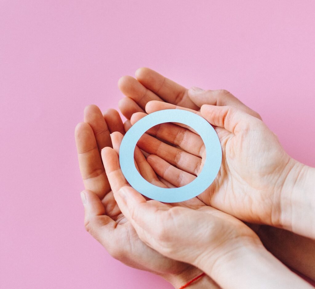 Two hands holding a blue circle symbolizing diabetes awareness against a pink background.